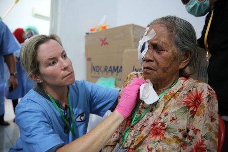 A New Vision volunteer helping a patient